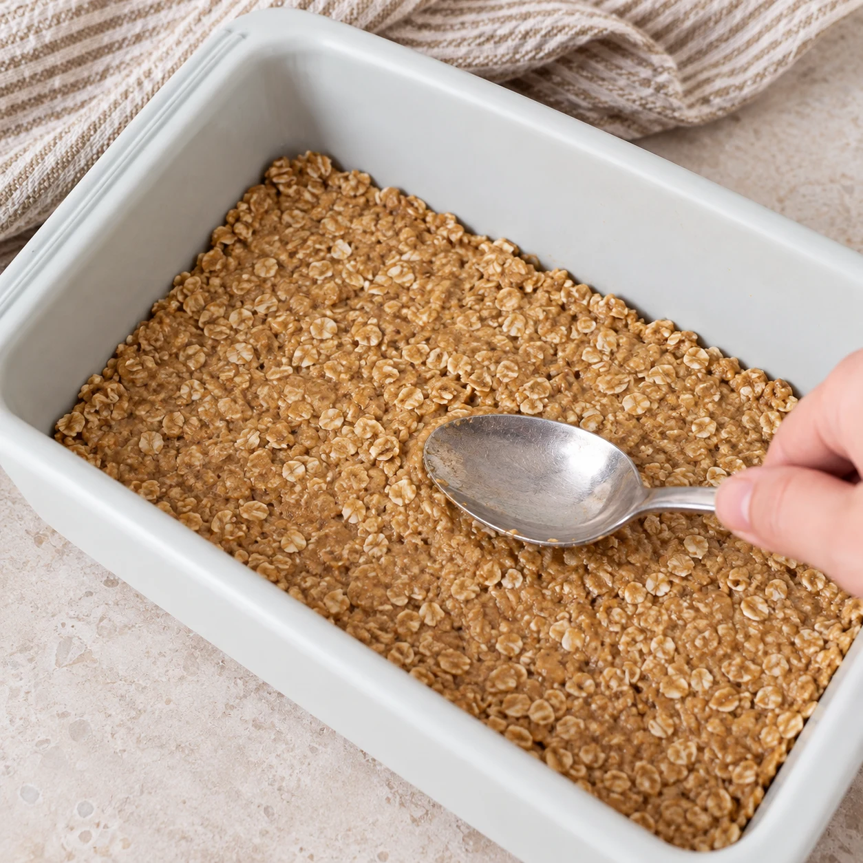 Étale et tasse la pâte avec le dos d’une cuillère dans un moule rectangulaire, comme dans la recette d’origine. État à montrer : La pâte couvre le fond en une couche compacte et régulière.