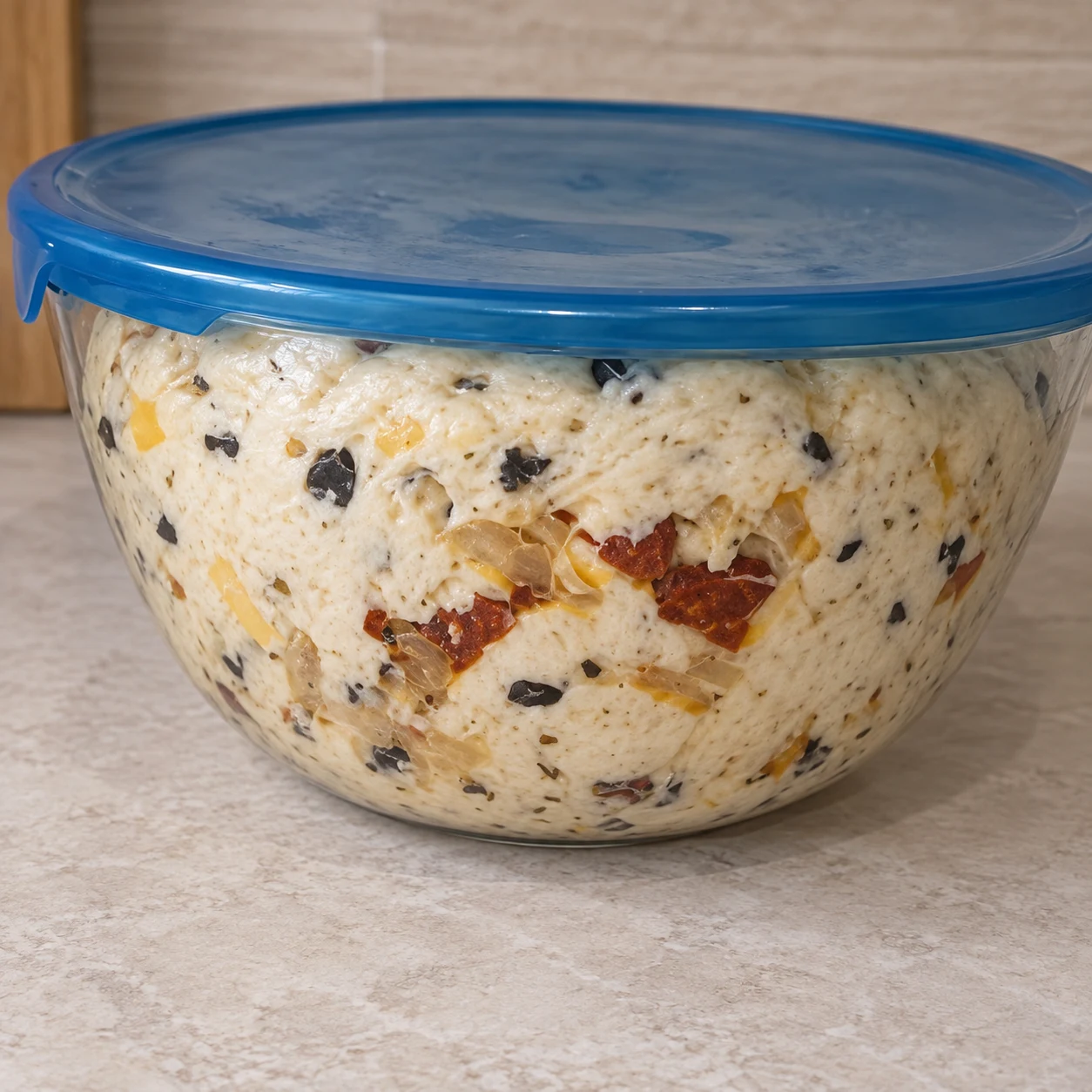 Laisser lever la pâte garnie. La pâte a visiblement gonflé sous le couvercle. Respecter la capture source ; chorizo et cheddar uniquement végétaux, aucune autre garniture.