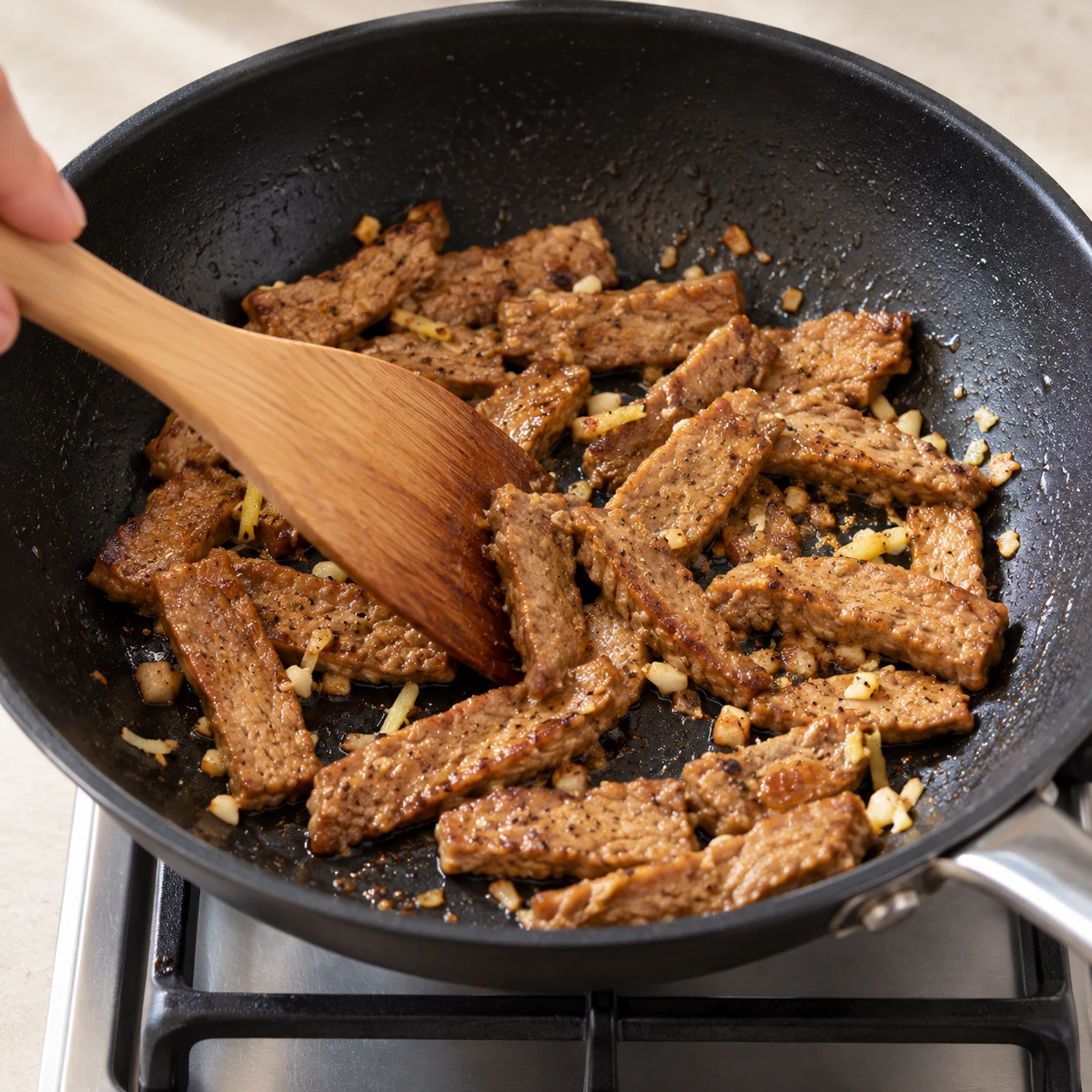 Ajoute les lamelles marinées de steaks de pois et fais-les sauter 1 minute, en les retournant délicatement. Les steaks ont déjà été cuits à cœur selon leur notice ; cette minute réchauffe les lamelles marinées.