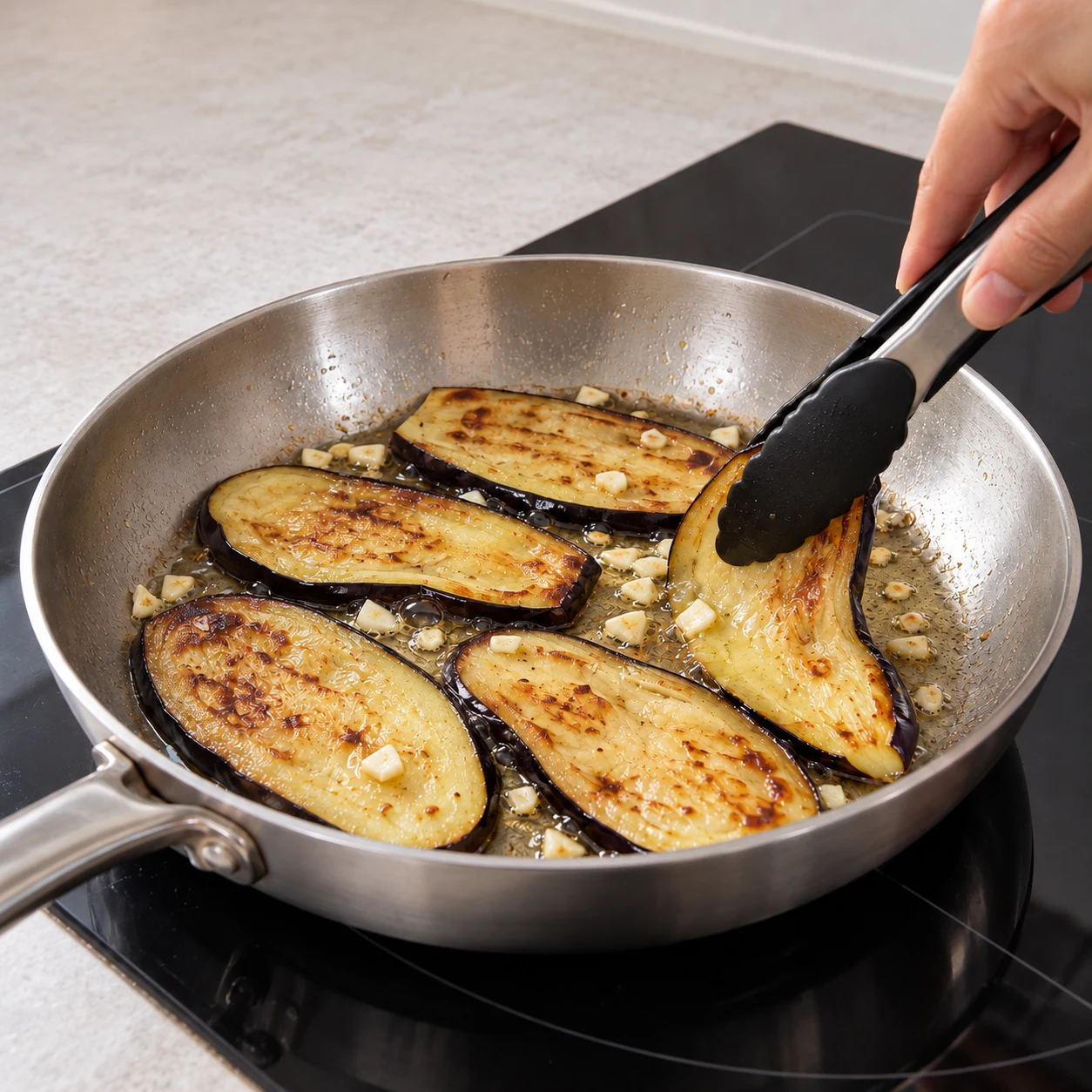 Fais revenir les lamelles d’aubergine avec l’ail et l’huile neutre dans une poêle. Retourne-les pour cuire les deux faces, jusqu’à ce que la chair soit tendre. Résultat visible : Les lamelles sont dorées et leur chair cède sous la spatule.