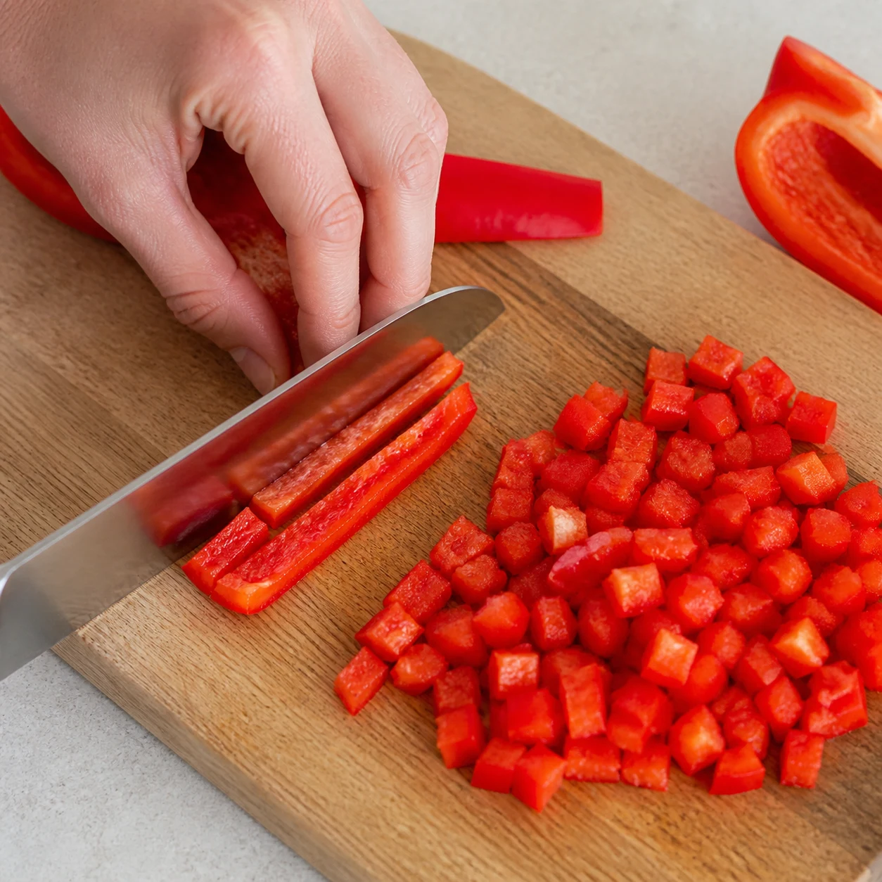 Poivron rouge coupé en petits dés sur une planche.