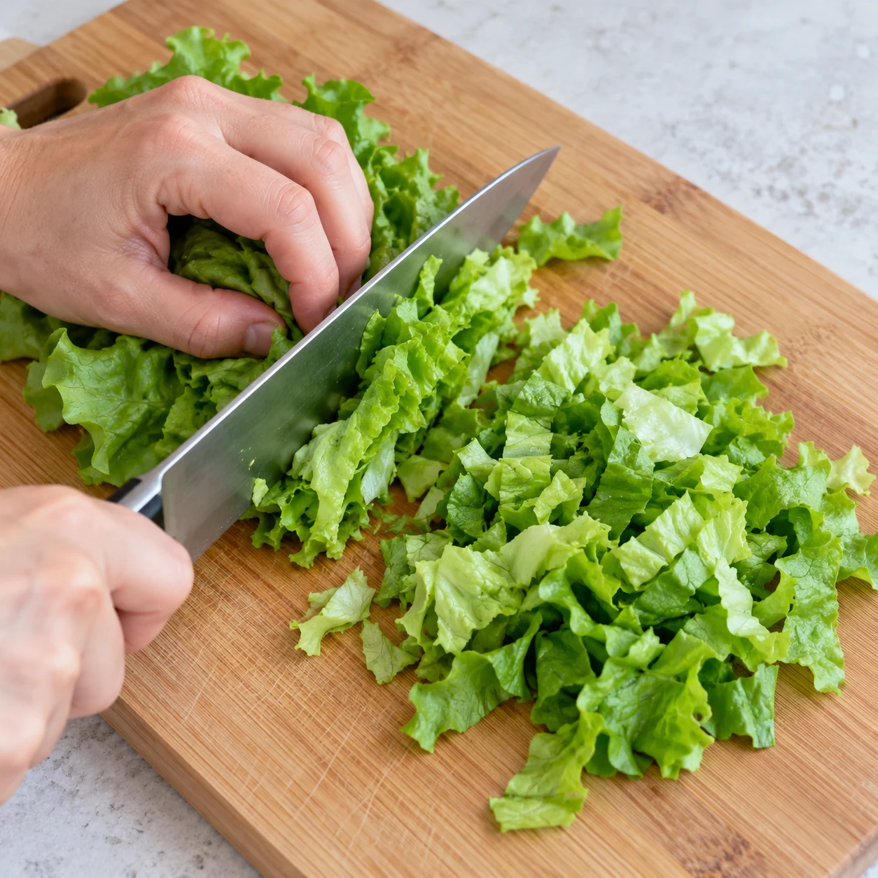 Photographie carrée de cette seule action ou son résultat : Découper la salade. Les feuilles sont découpées en morceaux faciles à manger. Seulement les ingrédients visibles de cette étape. La référence source contient du poulet : remplacer uniquement la protéine par les lamelles végétales de steaks pois et fèveroles. Aucun produit animal, texte ni personne identifiable.