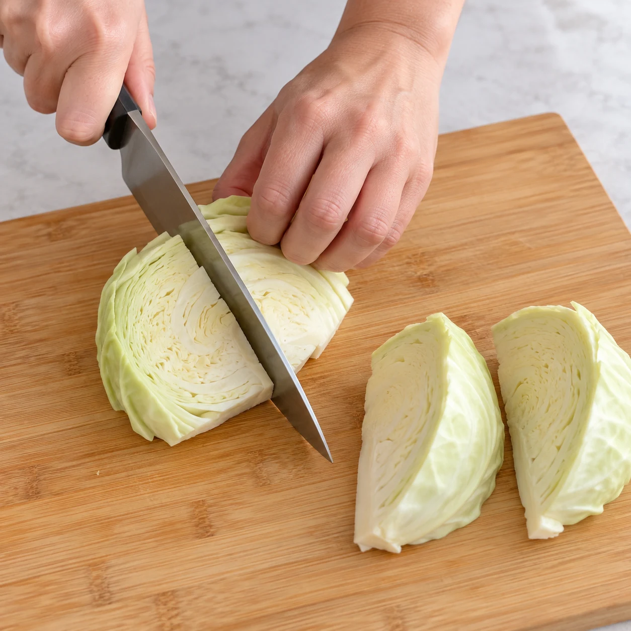 Posez le demi-chou blanc à plat sur une planche stable et coupez-le en quatre morceaux, comme dans la recette d’origine.