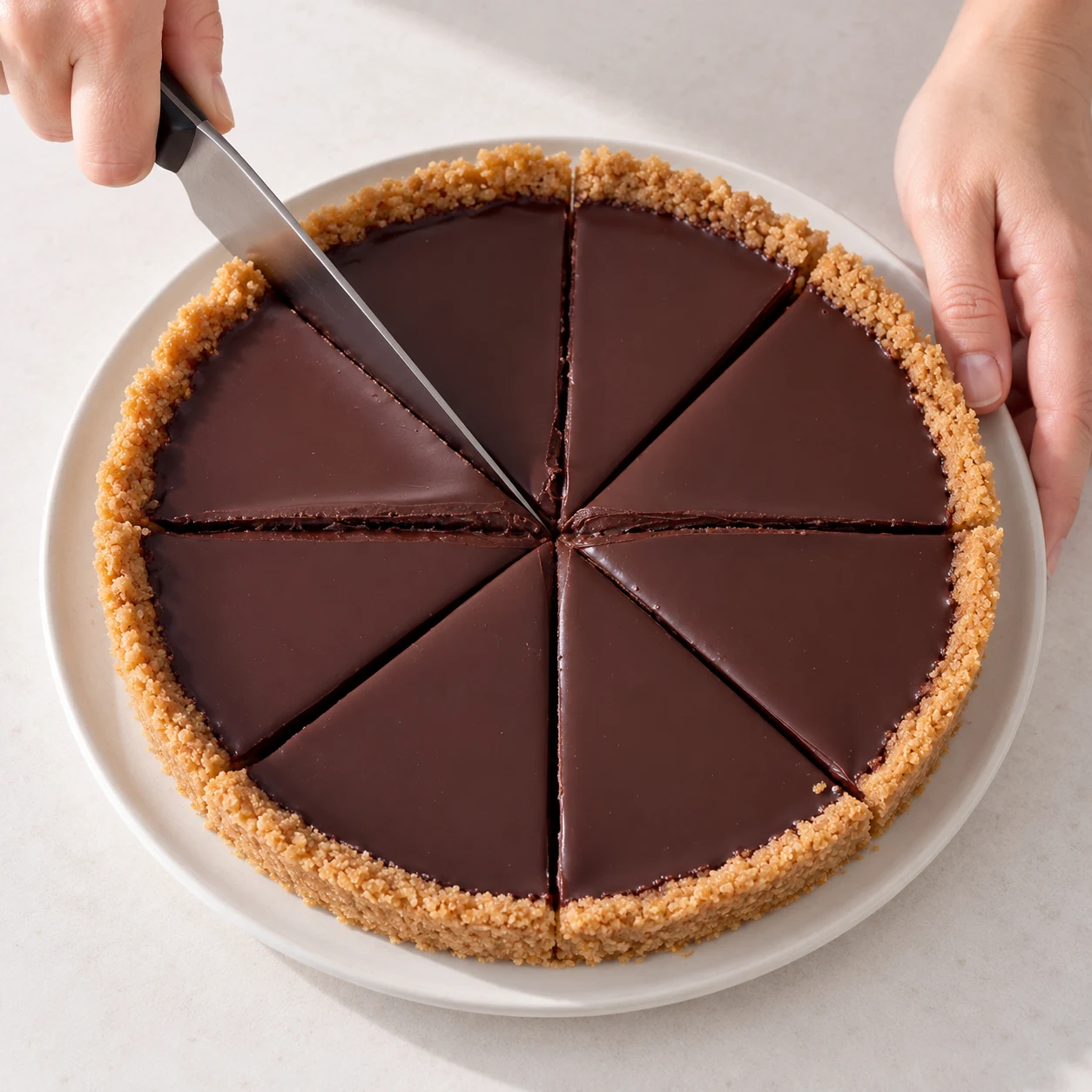 Découpe la tarte froide en huit parts, comme le découpage montré au début de la recette d’origine. Résultat à montrer : Huit parts sont découpées ; chaque part garde sa couche de ganache sur son fond de biscuits.