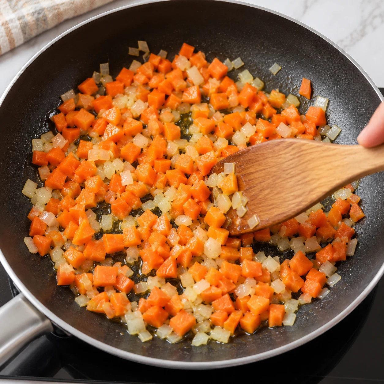 Cuisson composite dans poêle noire, carottes en petits dés avec oignons hachés et fine couche d’huile.