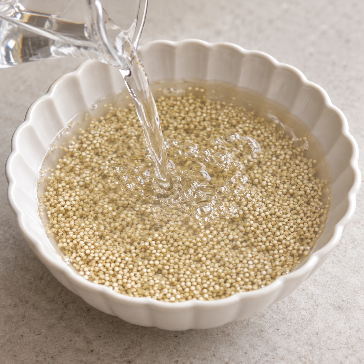 Quinoa cru couvert d’eau dans un bol blanc ; pas de flocons d’avoine ni de lait.