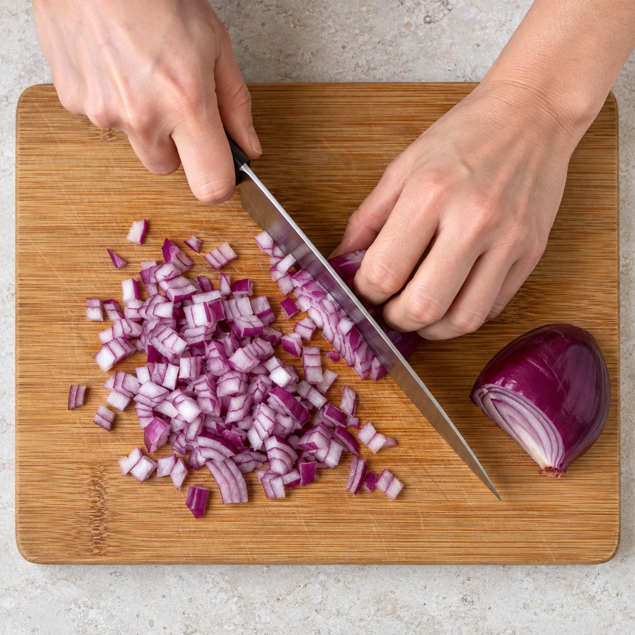 Une photographie carrée : Émince l’oignon rouge sur une planche stable, doigts repliés à distance de la lame. Résultat : L’oignon est découpé en petits morceaux.. Aucun ingrédient futur. Le Cayenne remplace le piment fumé original ; pas de piment fumé ajouté.