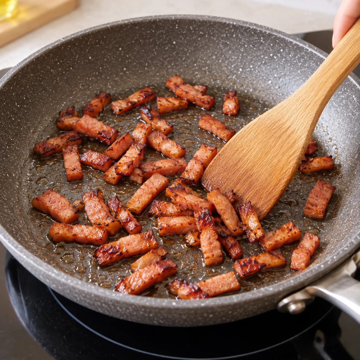 Poêle avec 50 g de lardons végétaux fumés aux bords dorés, spatule en bois.