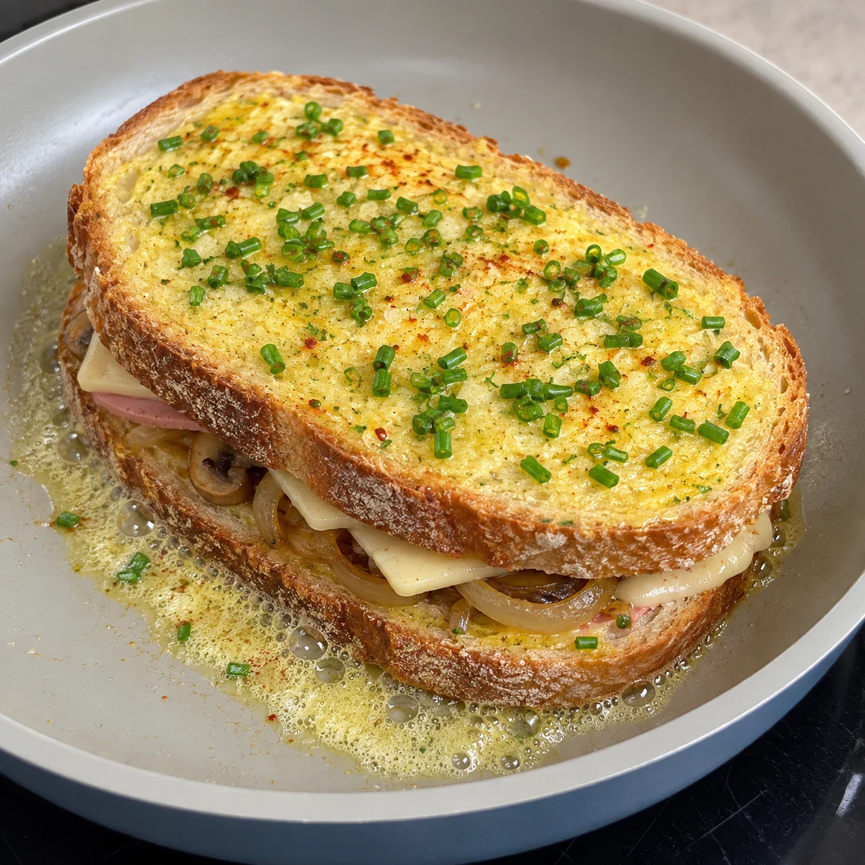Sandwich refermé dans la poêle, face supérieure jaune à la ciboulette.