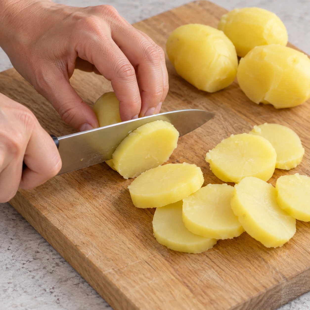 Couper les pommes de terre : Coupez les pommes de terre cuites en rondelles, sur une planche stable. Résultat : Les pommes de terre sont découpées en rondelles.