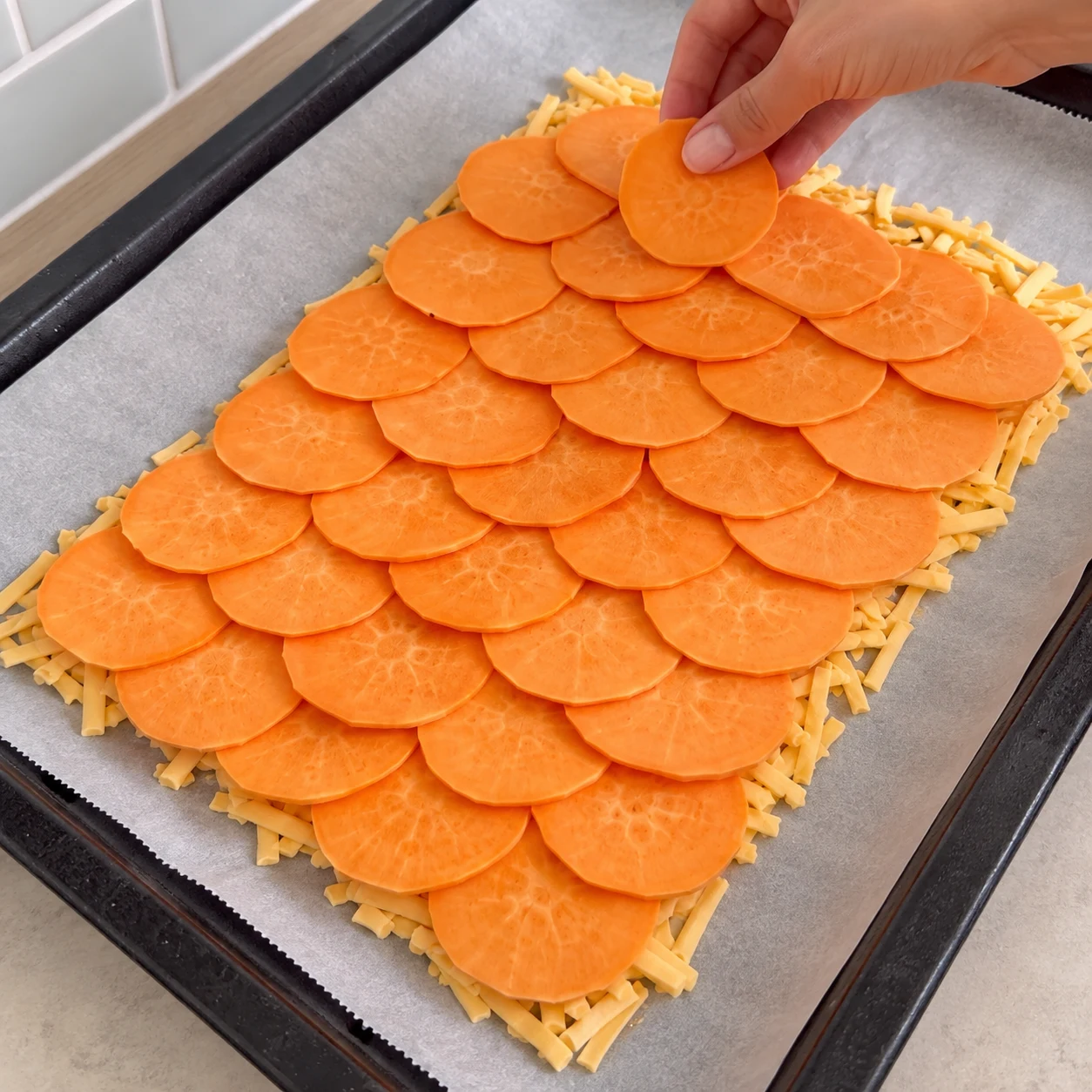 Mains anonymes disposant des rondelles orange qui se chevauchent sur une couche végétale fondante.