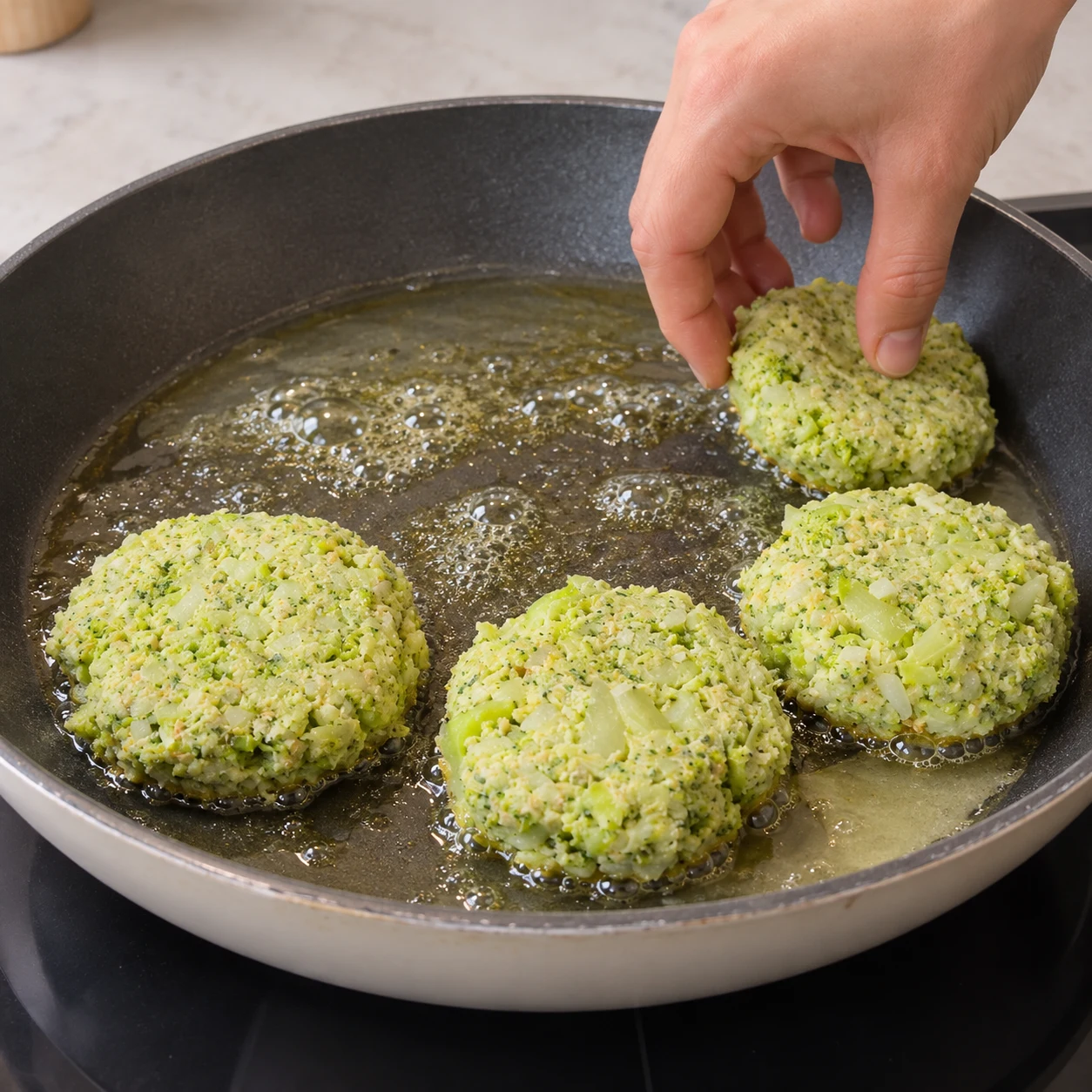 Galettes vertes en petits morceaux dans une poêle huilée, première face en cuisson.
