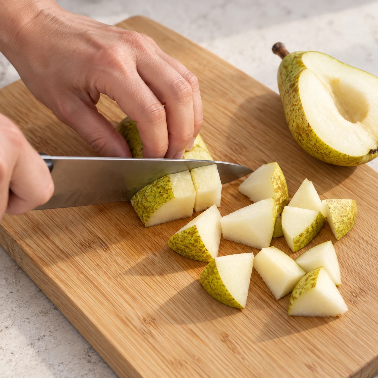 Découpe sûre d’une poire verte avec peau en morceaux sur planche ; main en griffe, couteau, aucune noix ni chocolat.