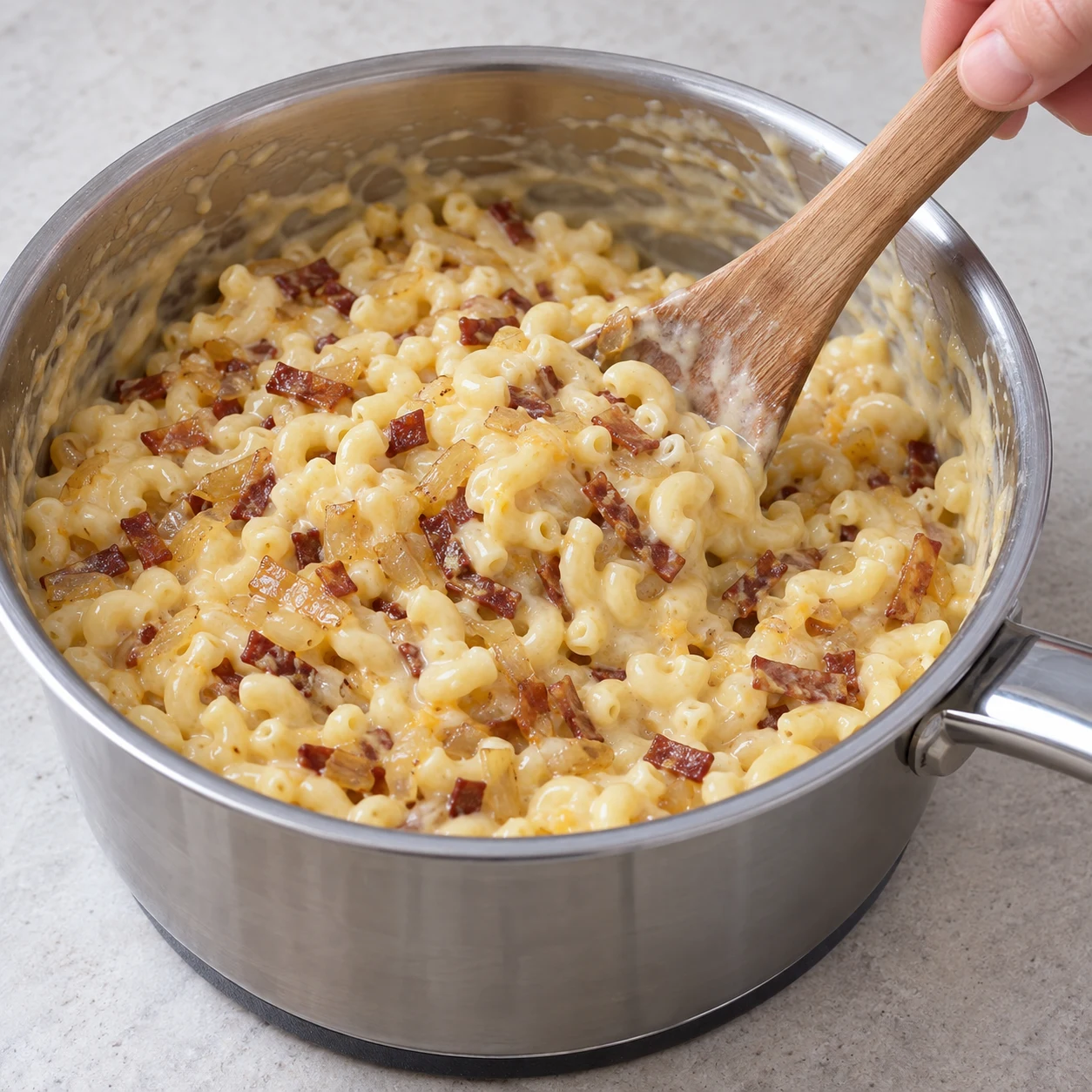 Verser mélange oignon et lardons fumés dans pâtes crémeuses.
