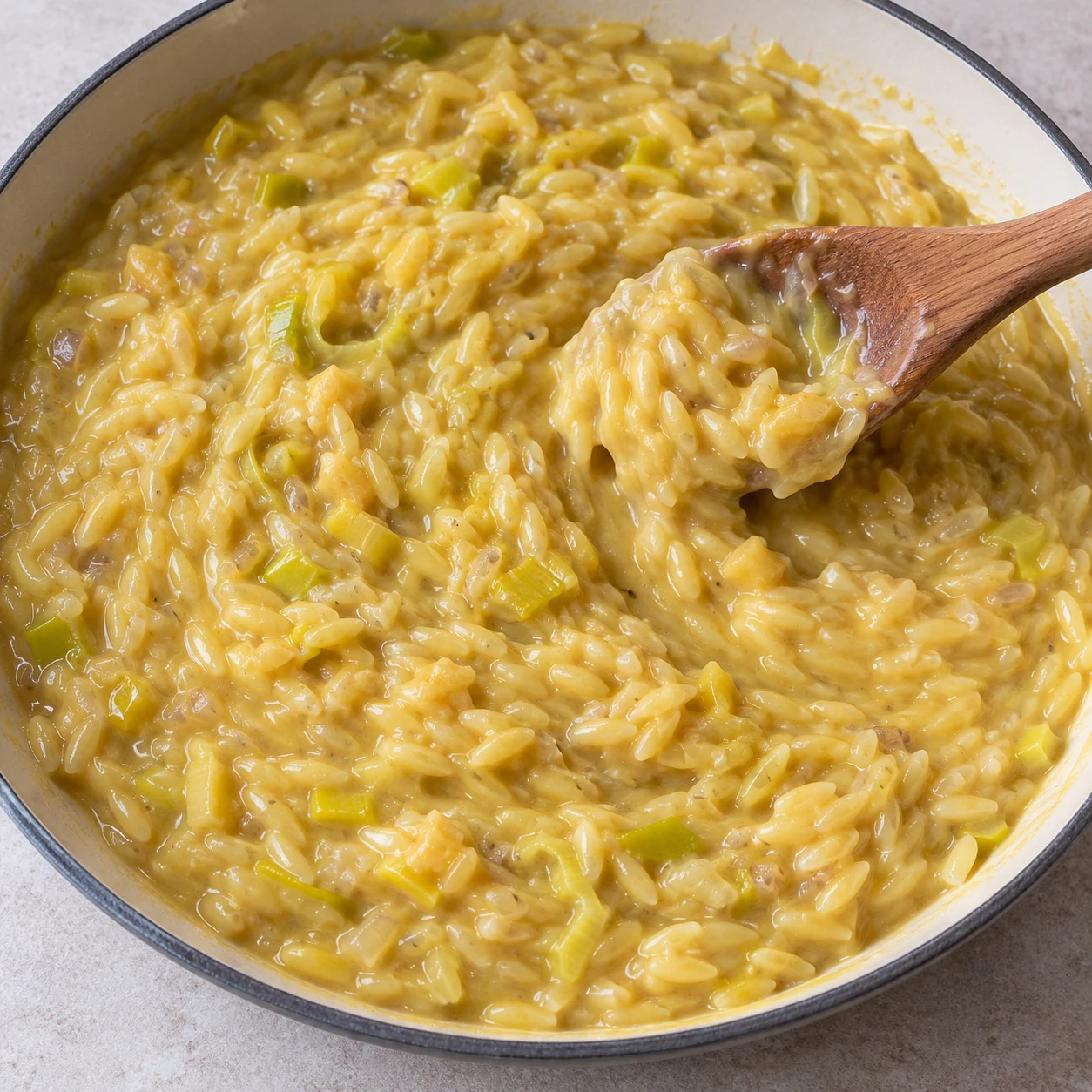 Finir la cuisson de l’orzo. Les pâtes sont tendres et liées par une sauce crémeuse.. Reproduire une seule action, ingrédients exacts et phase exacte. Adapter les crevettes visibles en pois chiches cuits entiers uniquement après son ajout. Aucun ingrédient futur.