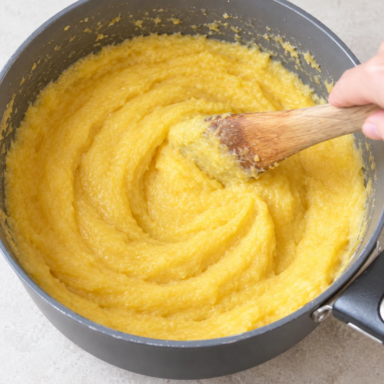 Spatule mêlant une noix pâle de margarine végétale à la polenta jaune crémeuse.
