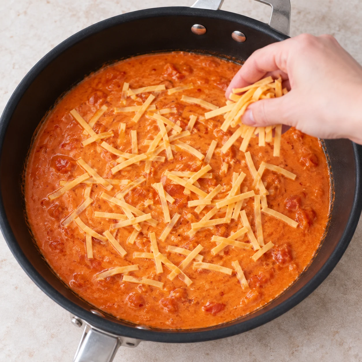 Parsème la sauce de fines lanières de fromage végétal. Les fines lanières de fromage végétal sont réparties sur la sauce.