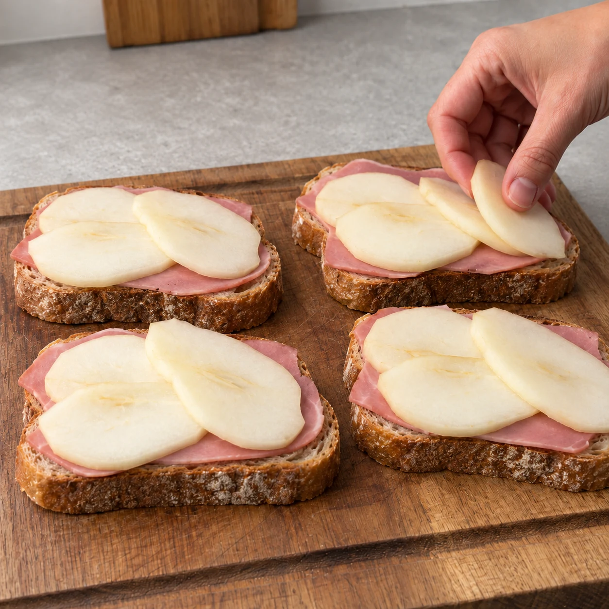 Répartis les lamelles de poire sur le jambon végétal. Montrer seulement les ingrédients de cette étape, les alternatives véganes acceptées et des mains adultes anonymes si nécessaire.