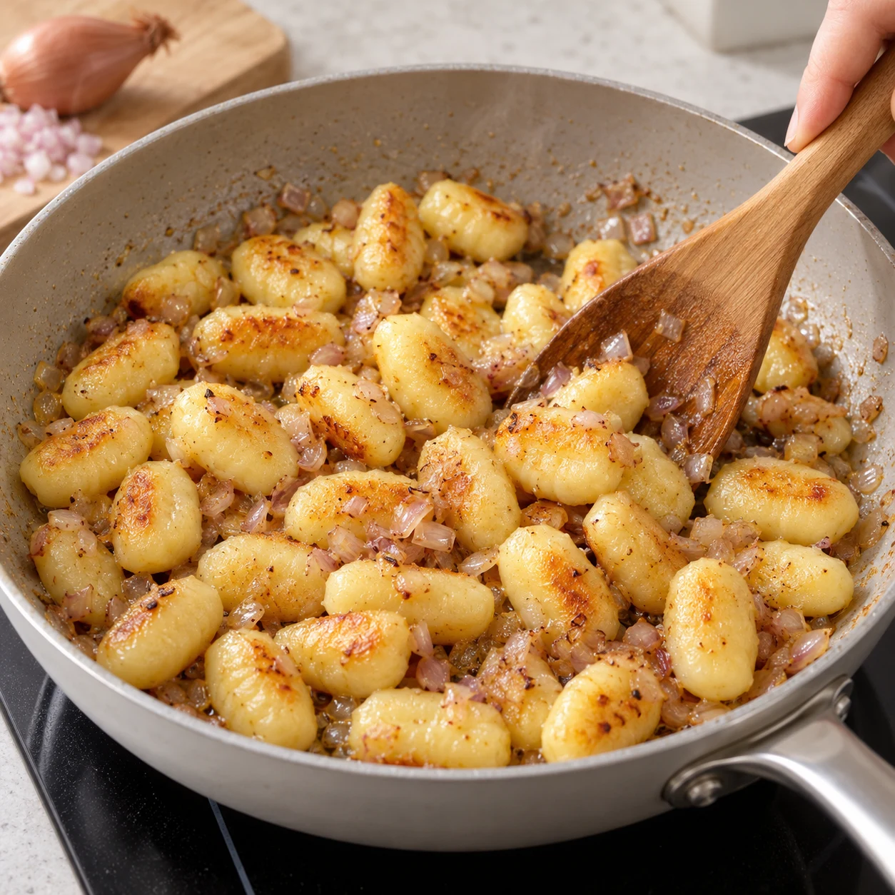 Ajoute les gnocchis et l’échalote hachée dans la poêle. Remue jusqu’à ce que les gnocchis soient dorés et l’échalote cuite.