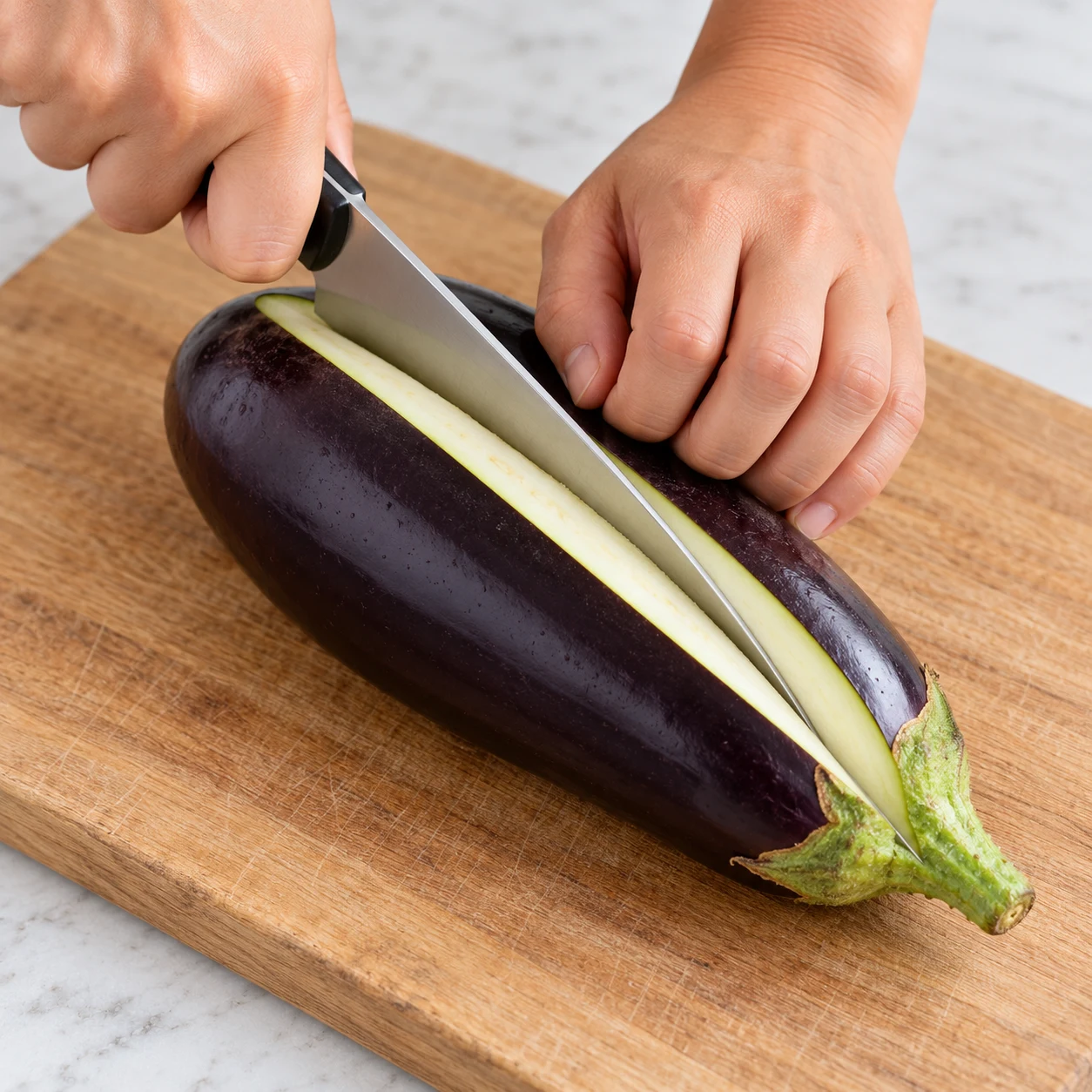 Coupez les deux aubergines en deux dans la longueur sur une planche stable. Gardez les quatre demi-aubergines.