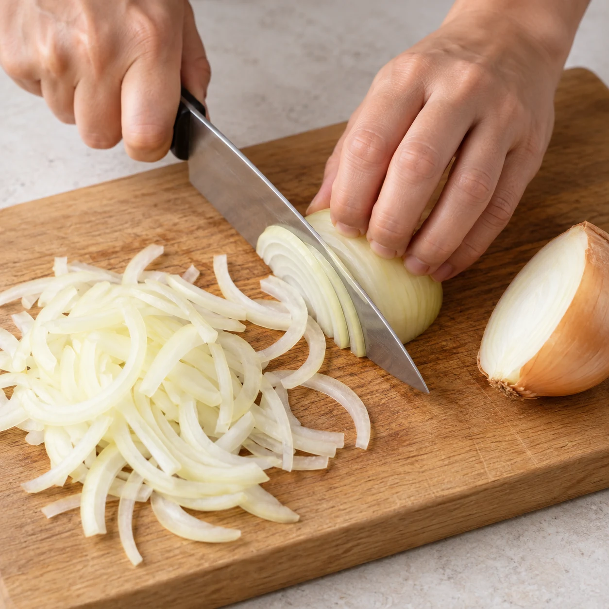 Main adulte anonyme en prise en griffe éminçant un oignon jaune sur une planche, sans carottes.