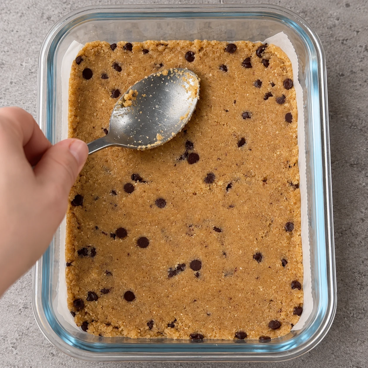 Tasse la pâte le plus fermement possible avec le dos d’une cuillère. État à montrer : La base forme une couche compacte et régulière, jusque dans les coins.