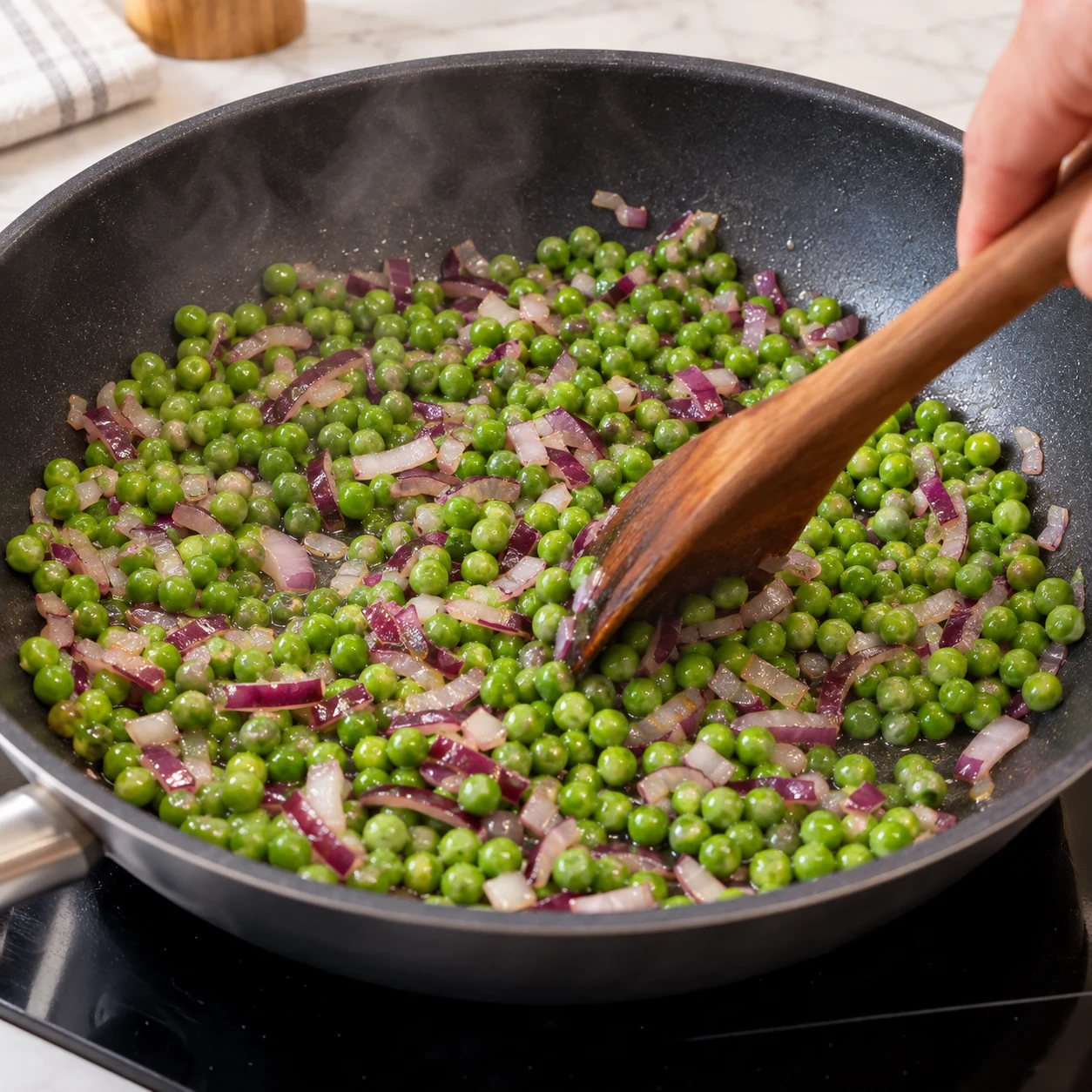 Faire revenir les petits pois : Les petits pois sont tendres, verts et répartis dans l’oignon.