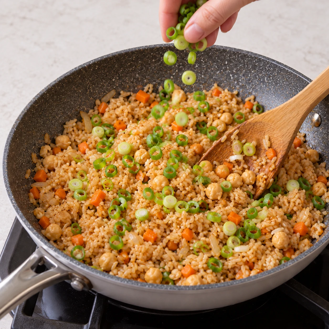 Ajoutez les cébettes émincées à la fin et répartissez-les dans le riz. État attendu : Les rondelles vertes sont réparties dans le riz. Une seule scène de cuisine, sans personne identifiable.