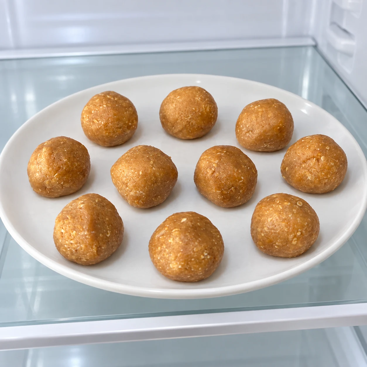 Dix boules beiges non enrobées sur une assiette neutre, au frais.