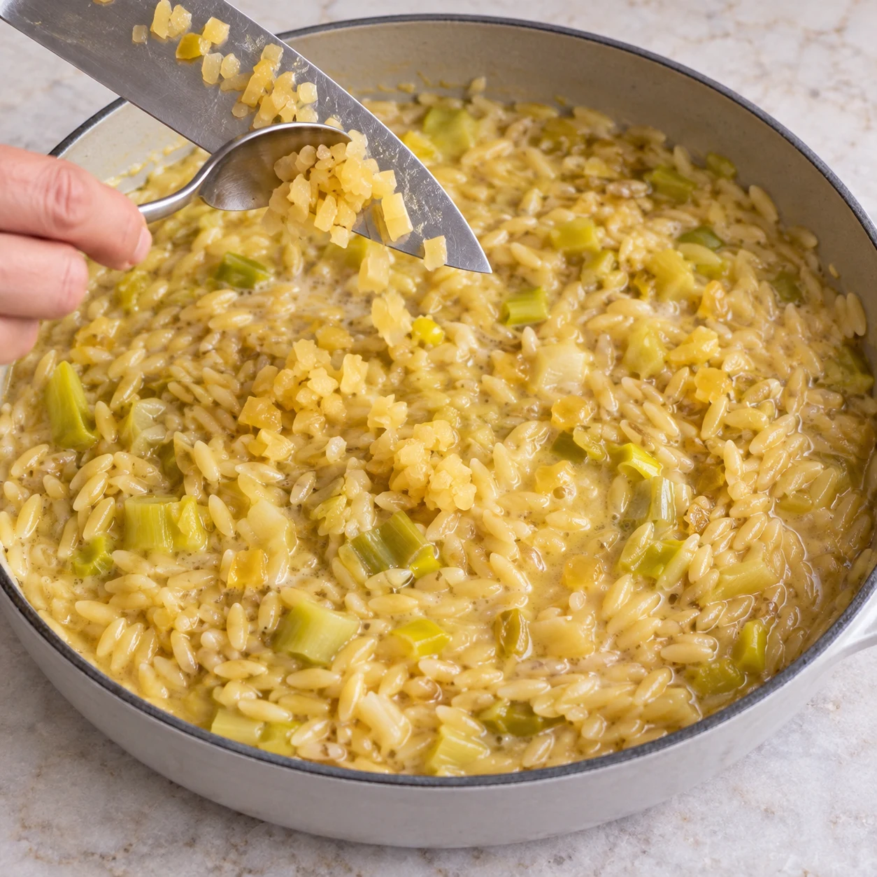 Incorporer le citron confit. Les petits morceaux de citron sont répartis dans la préparation.. Reproduire une seule action, ingrédients exacts et phase exacte. Adapter les crevettes visibles en pois chiches cuits entiers uniquement après son ajout. Aucun ingrédient futur.