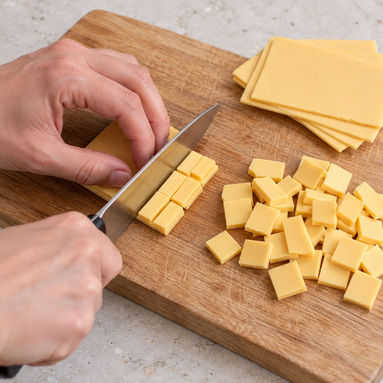 Tranches végétales saveur cheddar jaune pâle découpées en petits carrés sur une planche. Aucune feta blanche.
