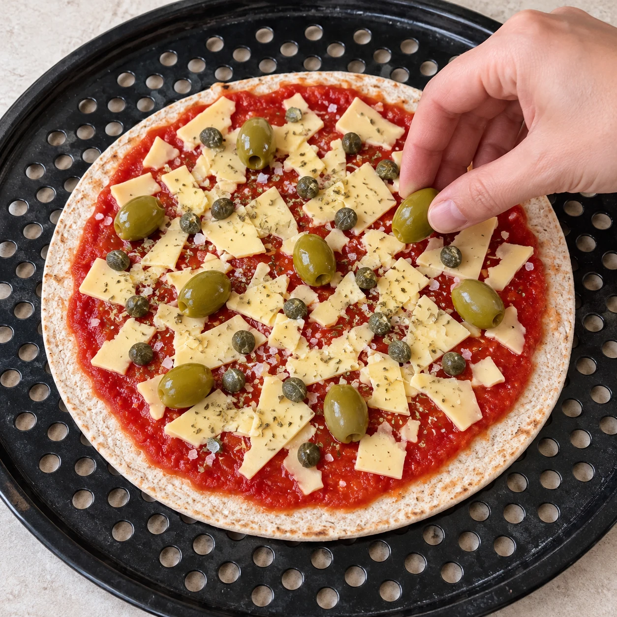 Petites câpres gris vert et olives vertes entières réparties sur les morceaux végétaux et la tomate crus.