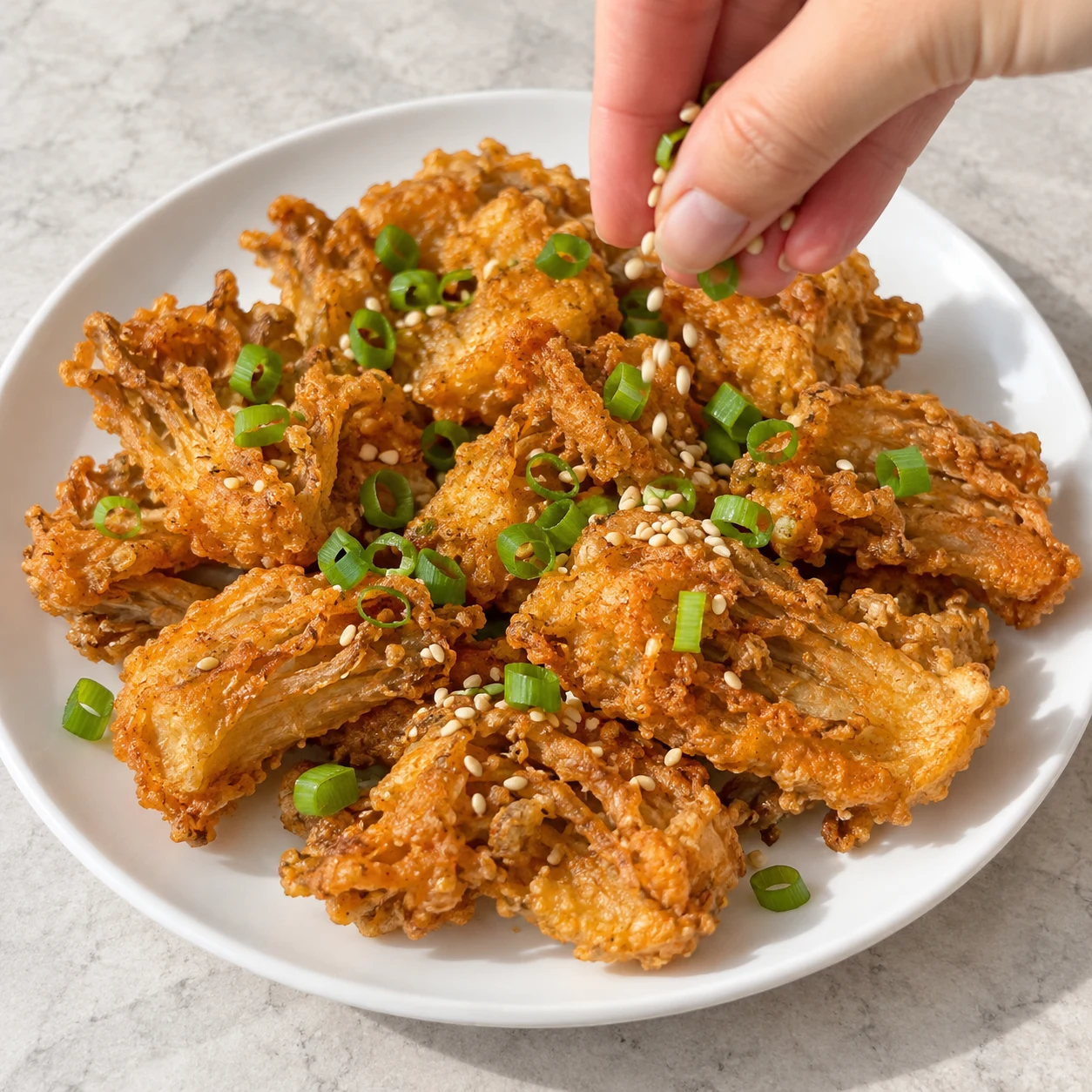 Une main anonyme parsème des nuggets dorés de cébette verte et sésame.