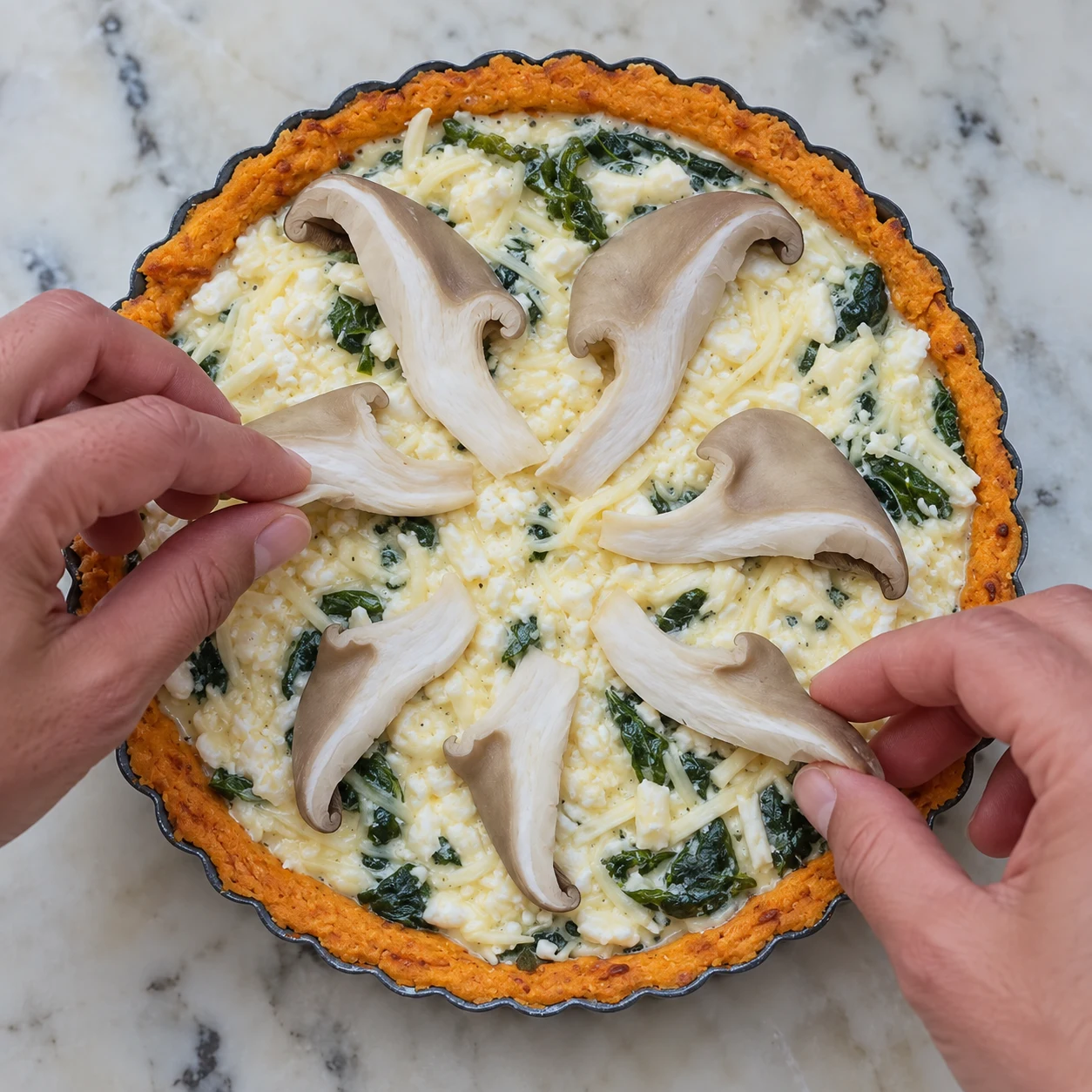 Mains anonymes déposant pleurotes sur quiche non cuite.