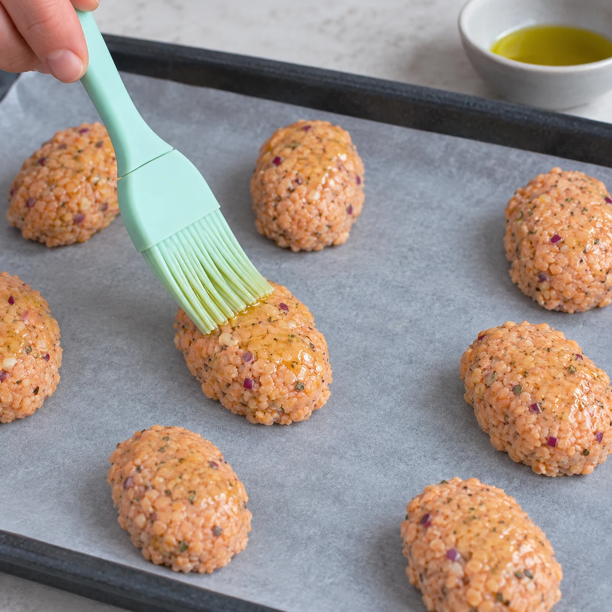 Badigeonner d’huile d’olive : Badigeonnez chaque falafel d’huile d’olive avec un pinceau. Résultat visible : Chaque falafel est légèrement huilé en surface. Une seule photo carrée de cette phase exacte ; aucun dip, garniture ou ingrédient futur.