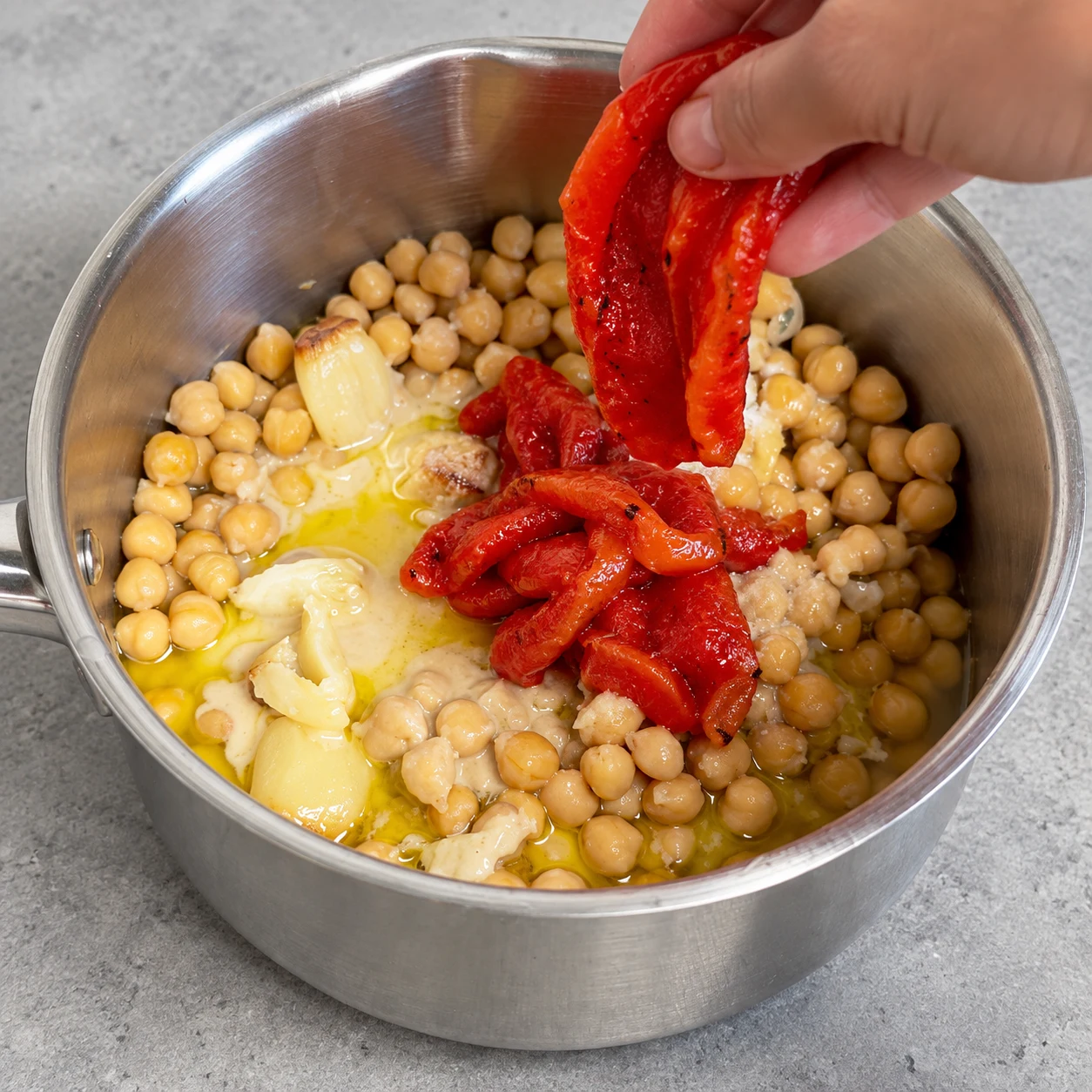 Ajouter le poivron grillé : Le poivron rouge rôti est dans le récipient avec les pois chiches.