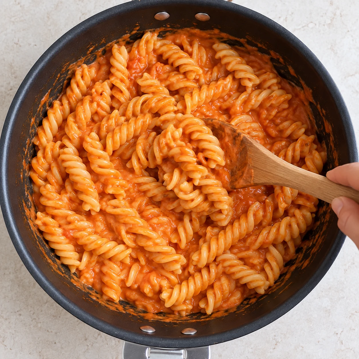 Ajoute les fusilli cuites al dente à la sauce et mélange pour les enrober. La sauce recouvre les spirales sans amas de pâtes sèches.