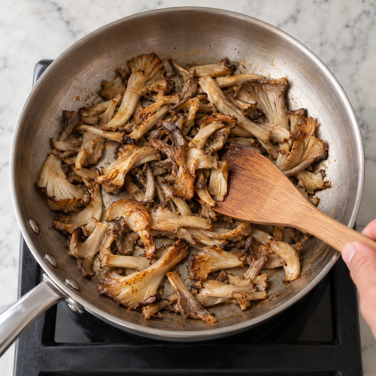 Pleurotes dorés dans grande poêle, spatule.