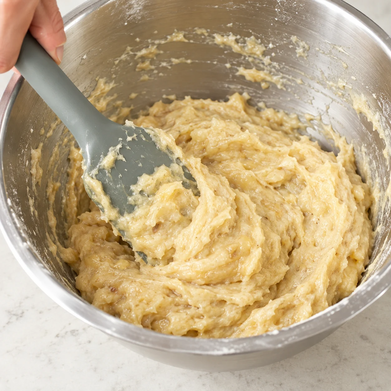 Une maryse incorpore de la compote de pomme beige à la pâte épaisse, sans œuf.