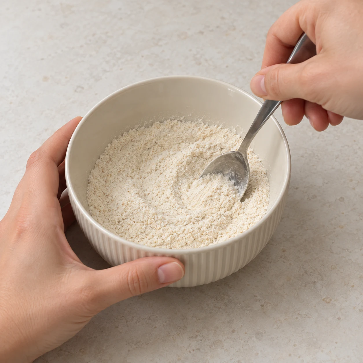 Bol neutre contenant une petite quantité de poudres ivoire mélangées à la cuillère.
