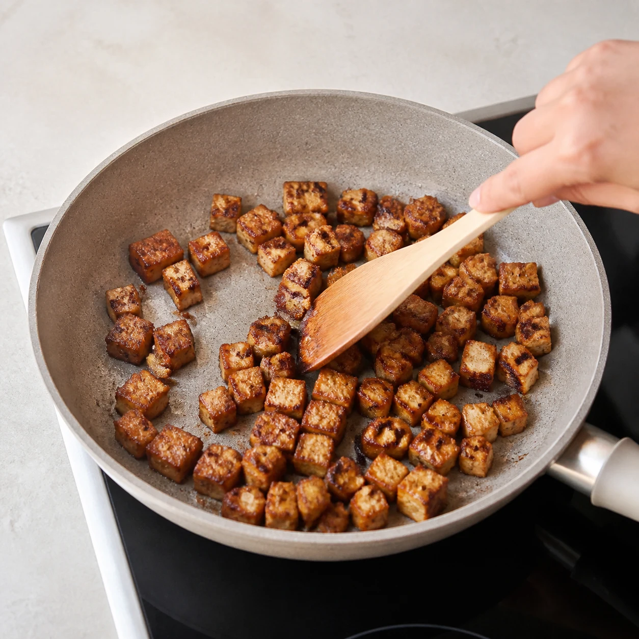 Dés de tofu fumé dorés dans une poêle.