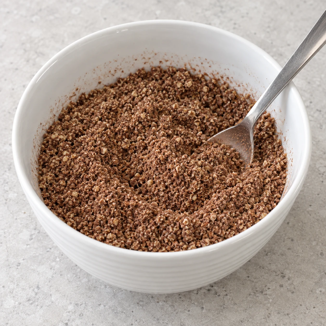 Bol blanc de noix moulues, poudre fine de graines de courge et cacao brun, mélangés à sec.