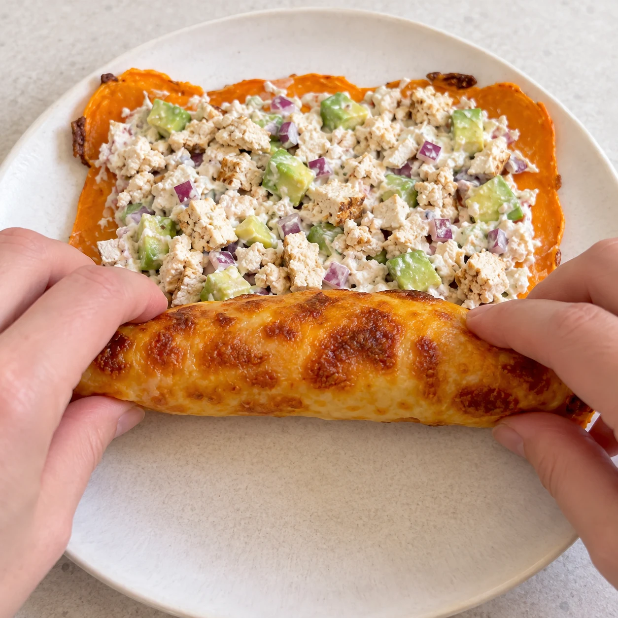 Roule délicatement la base garnie sur elle-même pour enfermer la farce, comme dans la recette d’origine. Montrer seulement les ingrédients de cette étape ; adaptation végétale, aucun saumon ni produit laitier.