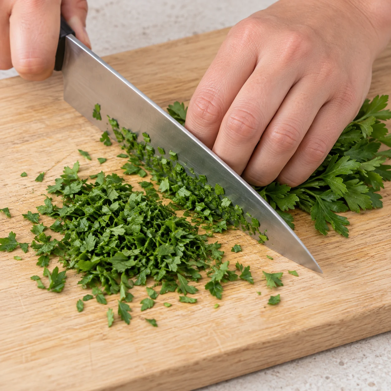 Hachage du persil frais, petites feuilles vertes sur planche claire.