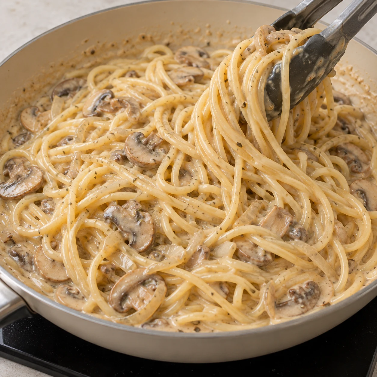 Incorporez les spaghettis égouttés à la sauce aux champignons. Montrer seulement l’action et cet état de cuisson.