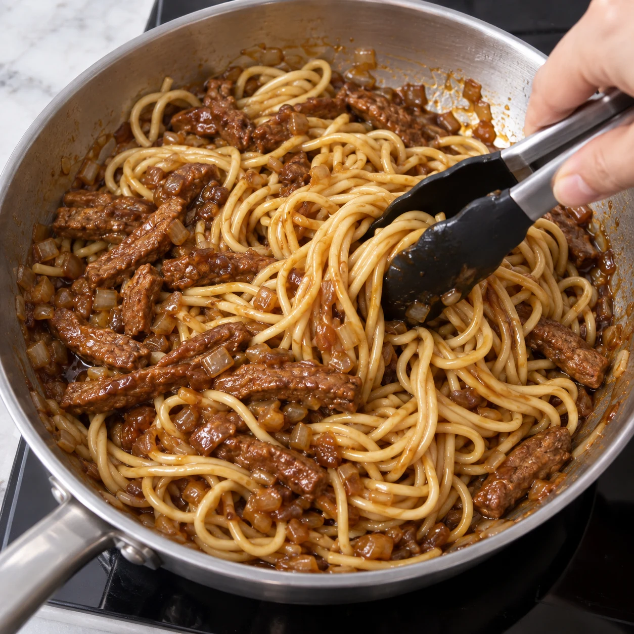 Main anonyme incorporant les nouilles cuites à la sauce avec les lamelles végétales et l’oignon, sans carottes ni ciboulette.