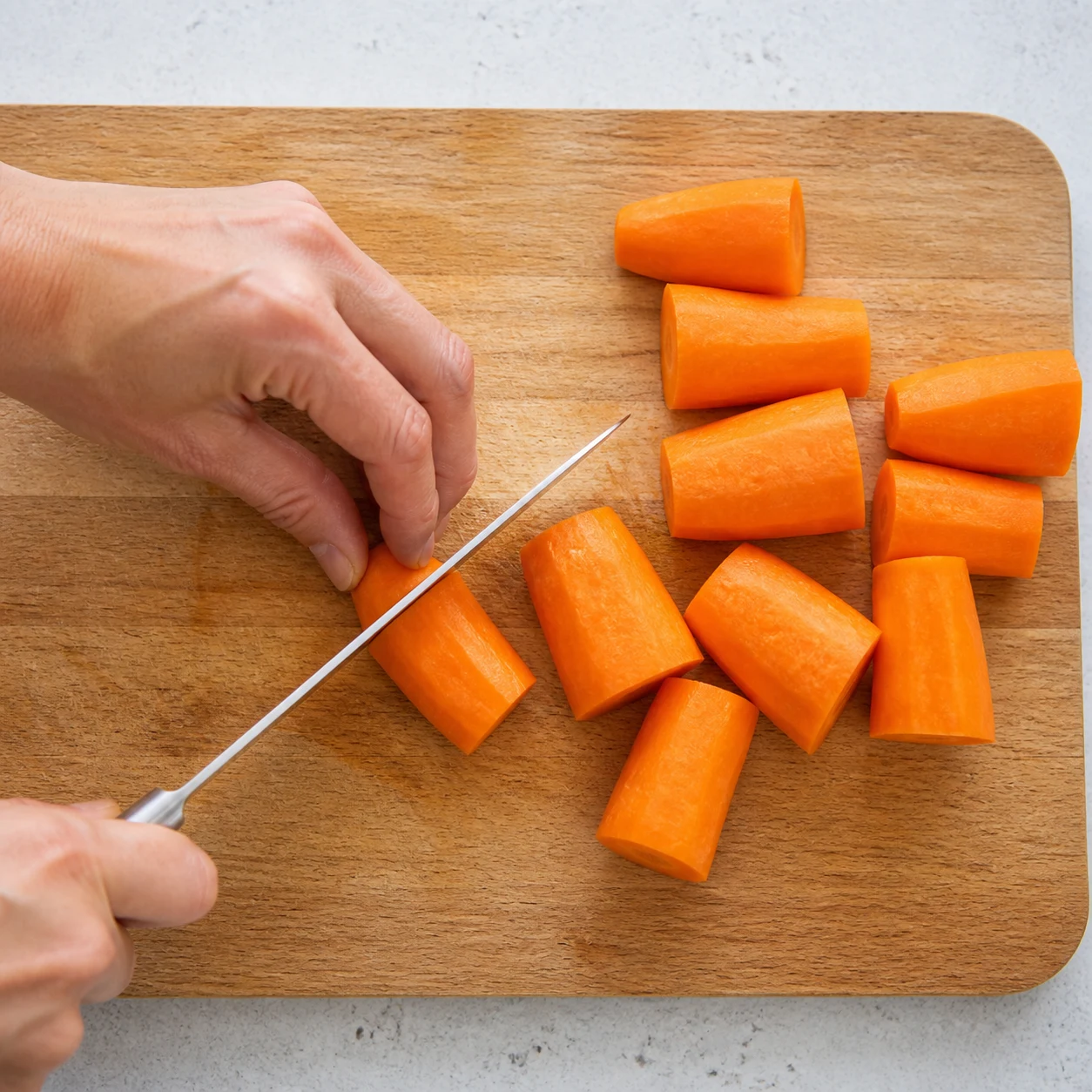 Planche en bois avec carottes découpées, couteau de cuisine, lumière naturelle.