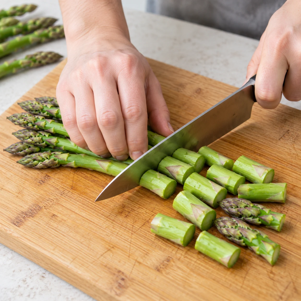 Tailler les asperges. Les tronçons sont réguliers et les pointes restent entières. Une seule action, cadrage carré, aucun texte ni personne identifiable.