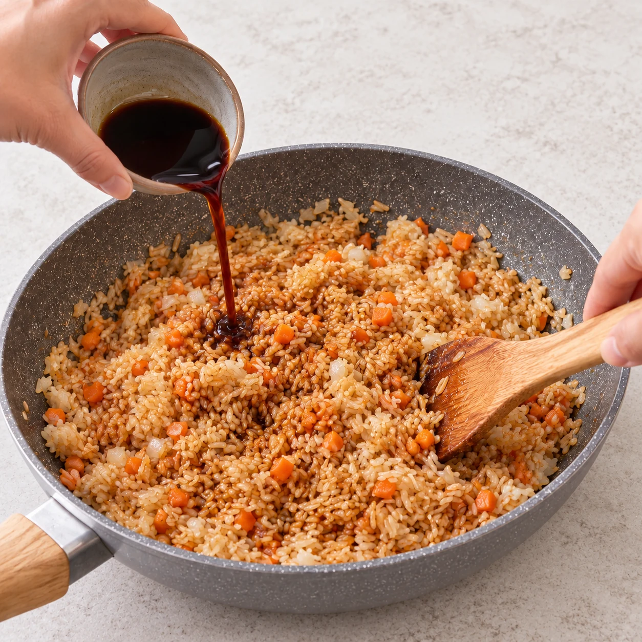 Versez les 2 cuillères à soupe de sauce soja, les 16 g de sauce soja remplaçant la sauce huître et une lichette d’huile de sésame. Mélangez pour enrober le riz. État attendu : La sauce colore les grains sans laisser une flaque au fond. Une seule scène de cuisine, sans personne identifiable.