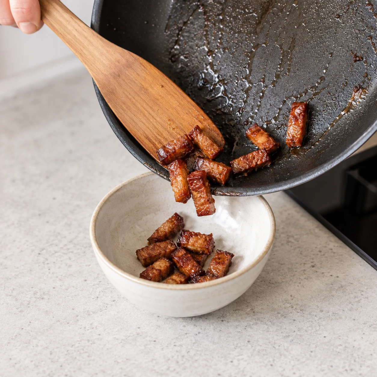 Lardons végétaux dorés transférés de poêle dans petit bol neutre.